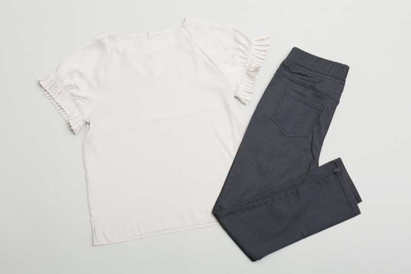 袖にフリルのついたベージュのブラウス、紺のサブリナパンツの写真