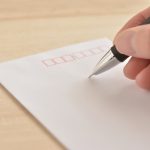インターンのお礼状送付ように封筒の宛先を書いている手元