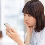 スマートフォンを見て考える女性