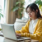 ノートパソコンを開いてメールの内容を考えている学生