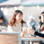 テラス席でコーヒーを飲む2人の学生